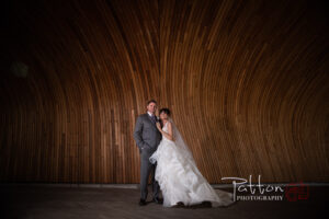 Calgary bride and groom in front of curved wooden wall